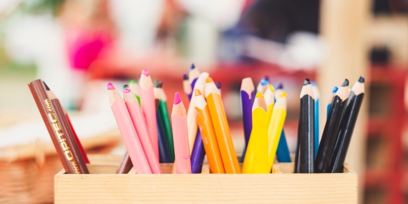 A wooden box containing assorted coloured pencils on a table, ideal for engaging toddlers in creative colouring activities.