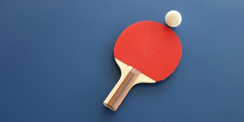 A blue table featuring a table tennis racket and ball, representing fun children's activities at church.