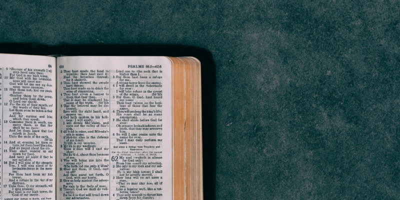 An open Bible lies on a dark table, representing a focused study session and spiritual exploration.