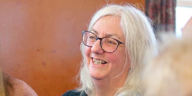 A woman wearing glasses engages in discussion during a women's Bible study at church, fostering connection and community.