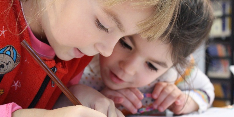 Two young girls drawing together at a children's club church in Salisbury, showcasing creativity and friendship.